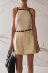 Woman wearing a beige dress with black straps against a marble background