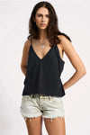 Woman wearing a black tank top and light denim shorts on a white background