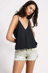 Woman wearing a black sleeveless top and denim shorts on a white background