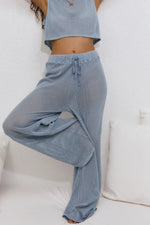 Person wearing blue checkered pants and a matching top on a white background