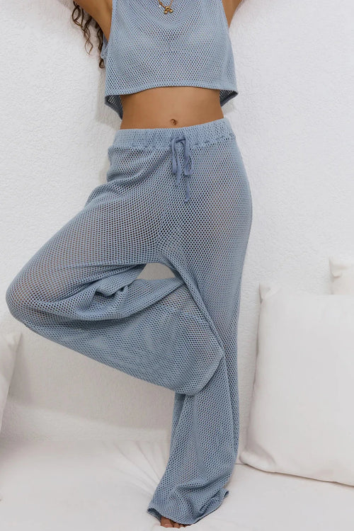 Person wearing blue checkered pants and a matching top on a white background