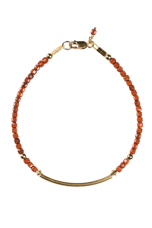 Bracelet with red beads and gold accents on a white background