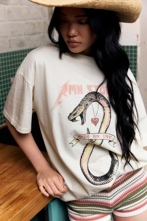 Person wearing a white t-shirt with a snake graphic design in an indoor setting.