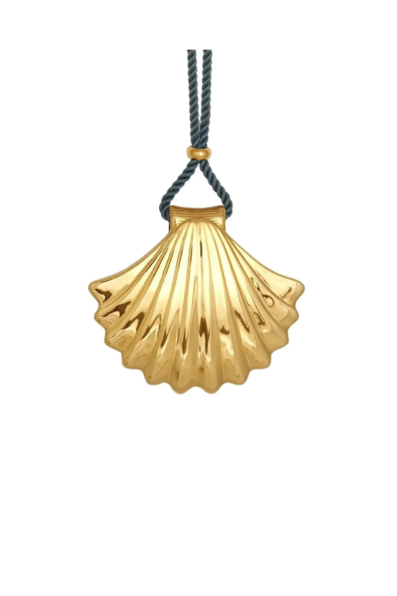 Gold scallop shell pendant on a blue cord against a white background
