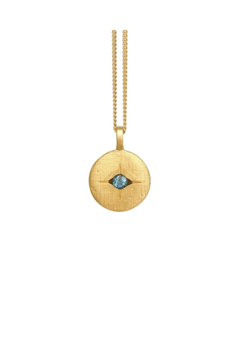 Gold necklace with a round pendant featuring a blue gemstone on a white background